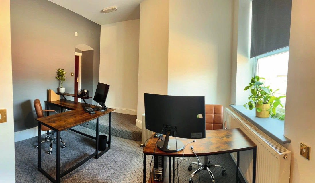 Furnished shared office at WorkHub @ The Hart, Headless Cross, with wooden desks, monitors, leather chairs and a plant by the window