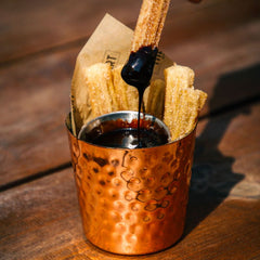 Golden cinnamon sugar churros served with rich chocolate dipping sauce in a copper cup at The Hart in Redditch