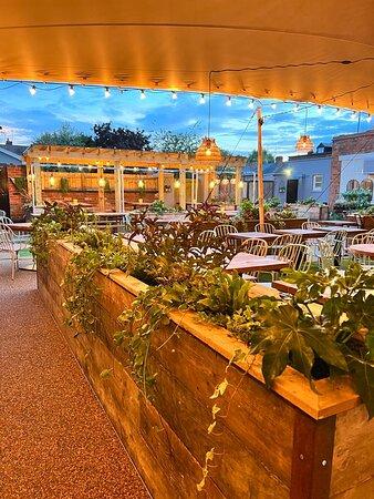 Raised wooden garden planters and outdoor dining tables in The Hart's covered courtyard in Headless Cross, Redditch, with cushioned bench seating.