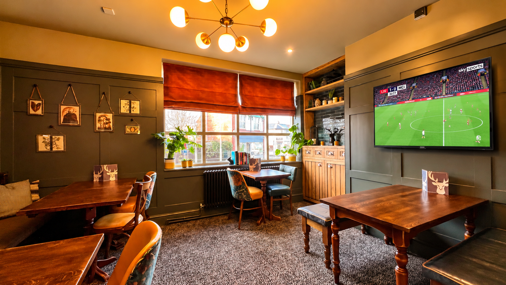 The Hart pub lounge in Headless Cross, Redditch, with a wall-mounted TV above the fireplace showing football